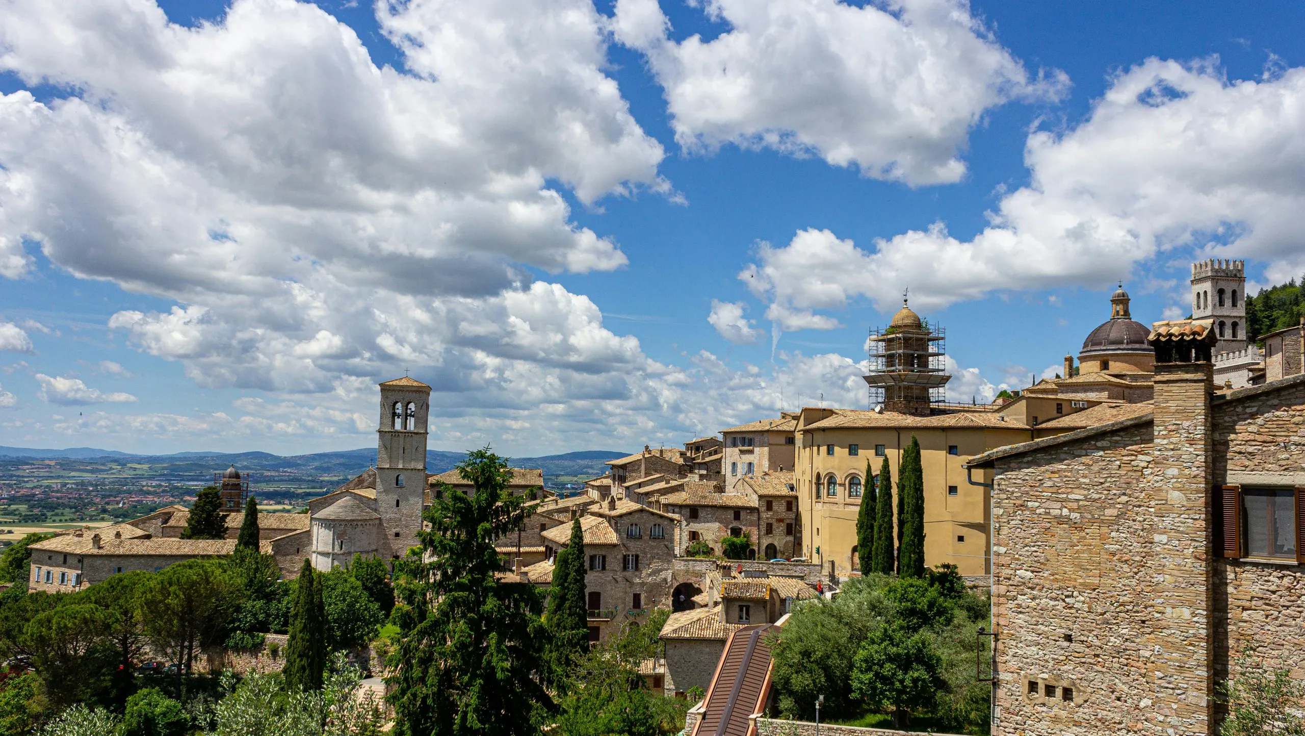 Wide panorama of Assisi old town with bell towers, domes and rolling hills
